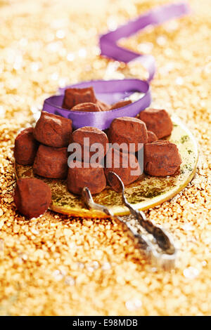 Truffes au chocolat avec un ruban sur un fond d'or de fête Banque D'Images