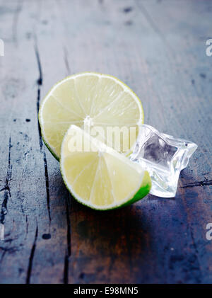 Deux citrons verts avec un cube de glace sur un sol en bois, ancienne base de boisson et Cocktail, surtout Caipirinha et concepts Mojito. Banque D'Images