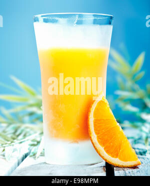 Grand verre de jus d'orange cocktail avec du jus fraîchement pressé contre un ciel d'été bleu Banque D'Images