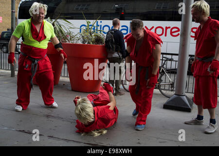 Les hommes sur un enterrement, déguisés en combattants kung fu blonde en rouge tenues arts martiaux combats pour s'amuser dans la rue. UK. Banque D'Images