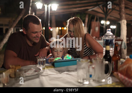 Les parents et l'enfant avec tablet PC in outdoor cafe Banque D'Images