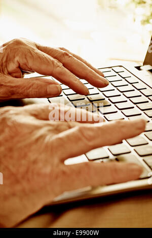 Les mains d'une personne senior à l'aide d'un ordinateur portable. Banque D'Images