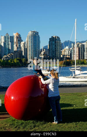 Jeune garçon assis sur l'amour vos beans sculpture par Cosimo Cavallaro, parc Charleson, False Creek, Vancouver, BC, Canada Banque D'Images