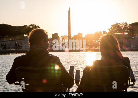 Couple sitting at lac de plaisance dans le jardin des Tuileries que les couchers de soleil derrière la Place de la Concorde sur un étés juin en fin de soirée,Paris Banque D'Images