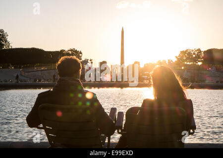 Couple sitting at lac de plaisance dans le jardin des Tuileries que les couchers de soleil derrière la Place de la Concorde sur un étés juin en fin de soirée,Paris Banque D'Images