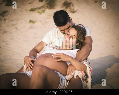 Happy pregnant woman on beach à l'extérieur. Couple est dans le sable. Banque D'Images