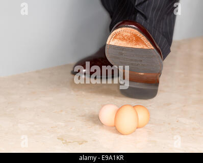 Man's shoe stamping sur trois oeufs Banque D'Images