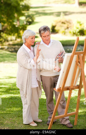 Couple de retraités peinture dans le parc Banque D'Images