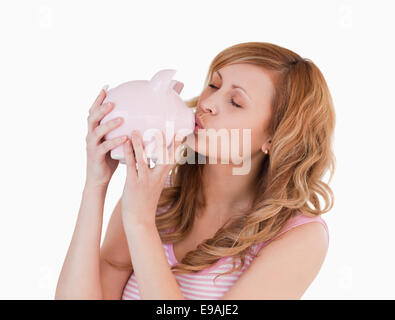 Blonde-haired woman kissing her piggybank Banque D'Images