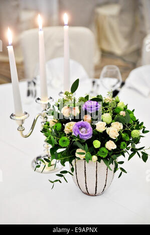 Arrangement de fleurs et un chandelier avec bougies allumées sur une table de dîner Banque D'Images