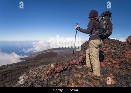 Randonneur sur le sommet du volcan Piton de la Fournaise avec vue sur les nuages et la mer, à la réunion Banque D'Images