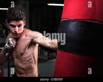 Young caucasian Boxer avec une formation dans son sac de gym à domicile Banque D'Images