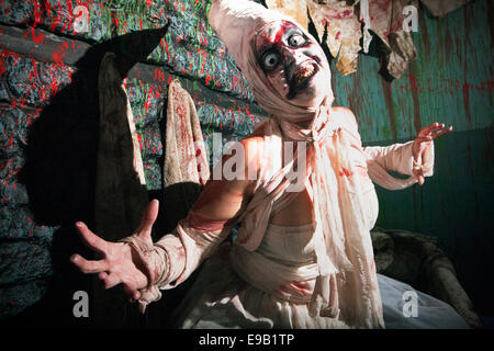 Blackburn, Royaume-Uni. 22 octobre, 2014. Et l'Halloween horreur masqués personnages costumés en masque latex préparer pour terrifier les visiteurs d'effrayer Royaume Scream Park attraction de l'événement nocturne Halloween Horror Nights 2014. Costume et maquillage- Unsettlingly aperçu effrayant dans leur propre droit, jusqu'à 50 acteurs en costumes et maquillage du visage complet offrent une pleine nuit de frissons, de sensations fortes, de terreur et de divertissement dans les locaux près de Preston dans le Lancashire, Royaume-Uni. Credit : Cernan Elias/Alamy Live News Banque D'Images