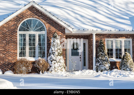 Maison individuelle en brique enfouie dans la neige et décorées pour Noël. Banque D'Images