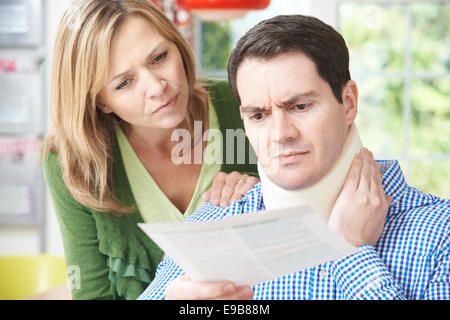 Couple Reading Lettre à l'égard du mari de la blessure au cou Banque D'Images