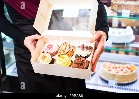 Femme présentant des muffins et cupcakes dans des boîtes à emporter dans la région de cafe ou pâtisserie Banque D'Images