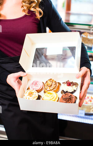 Femme présentant des muffins et cupcakes dans des boîtes à emporter dans la région de cafe ou pâtisserie Banque D'Images