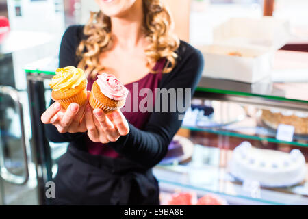 Femme présentant des muffins et cupcakes en boulangerie ou pâtisserie Banque D'Images