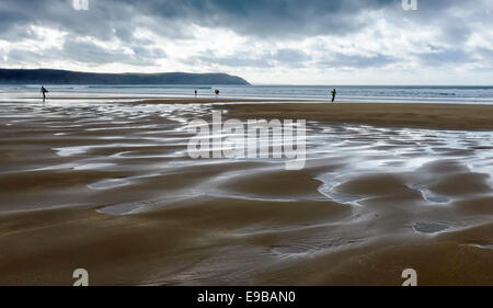 La paix et la tranquillité avec les surfers sur une plage de Woolacombe Sands orageux, North Devon, Angleterre. Banque D'Images