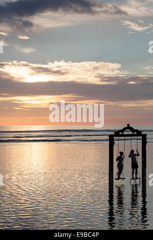 Silhouette de deux personnes sur swing de la mer au coucher du soleil, 'Gili Trawangan, Indonésie, des îles Gili Banque D'Images