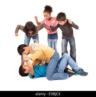 Garçons lutte avec d'autres enfants isolés d'encouragement en blanc Banque D'Images