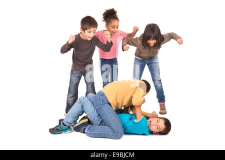 Garçons lutte avec d'autres enfants isolés d'encouragement en blanc Banque D'Images