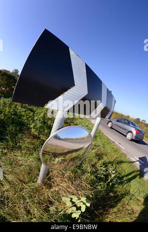 Une voiture passe panneau d'avertissement de virage et de sécurité circulaire miroir pour donner aux conducteurs qui sortent de l'affichage des intersections de routes uk Banque D'Images