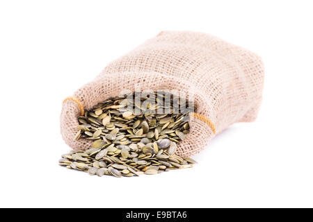 Gros plan du sac de jute renversé les graines de citrouille, isolé sur fond blanc. Banque D'Images
