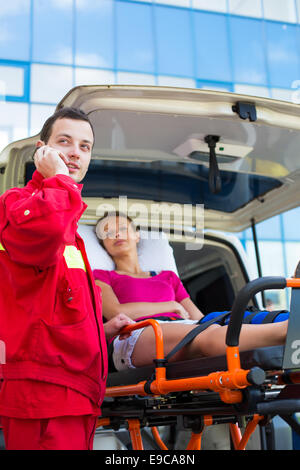 Paramedic s'occupant d'un patient de sexe féminin - appelant un hôpital Banque D'Images