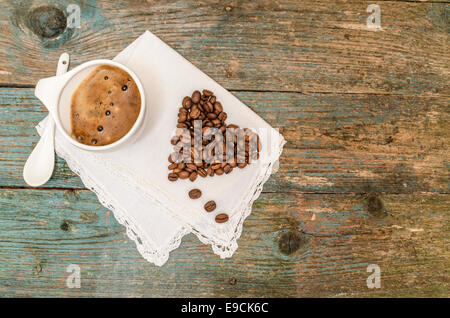 Coeur fait avec des grains de café et tasse de café sur fond de bois. À partir d'une série Coffee Time Banque D'Images