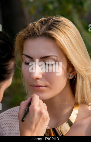 Jolie femme blonde au cours d'une séance de maquillage Banque D'Images