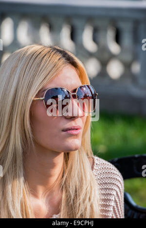 Jolie femme blonde portant des lunettes de soleil dans le parc Banque D'Images