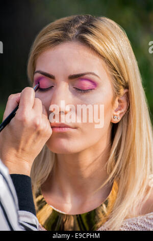 Belle jeune femme au cours d'une séance de maquillage avec de l'ombre à paupières rose Banque D'Images