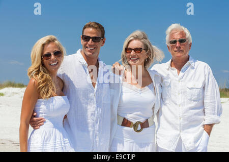Quatre personnes, deux personnes âgées, des couples ou des générations, portant des vêtements blancs ensemble s'amusant sur la plage tropicale locations Banque D'Images