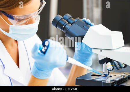 Belle femme dans un laboratoire avec un microscope. Banque D'Images