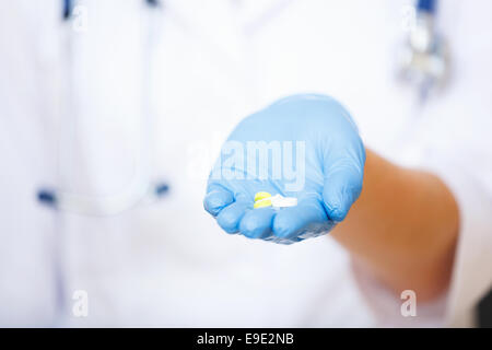 Main du médecin en bleu glove holding out comprimés. Banque D'Images