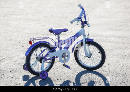 Les petits enfants vélo avec roues de formation à l'extérieur. Banque D'Images