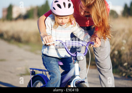 Redhead girl riding bike casque dans l'apprentissage. Banque D'Images