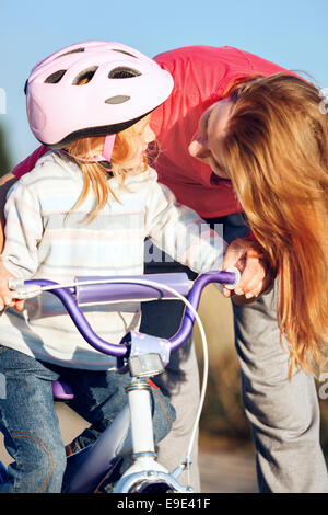 Redhead girl riding bike casque dans l'apprentissage. Banque D'Images