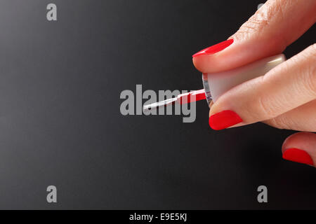 De Brosse à ongles manucurés rouge en femme palmiers sur fond noir. Banque D'Images