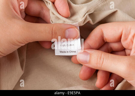 Woman's hands holding clothes label. 100 % coton. Fabriqués en Chine. Banque D'Images