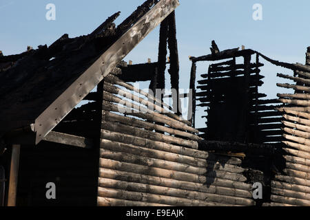 Close up Vaste maison en bois endommagés Incendie, soulignant la crête, avec fond de ciel bleu clair. Banque D'Images