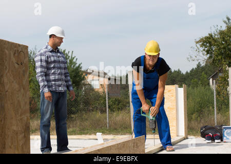 Les hommes d'âge moyen de la supervision Ingénieur professionnel Travailleur de la construction en cours de forage sur le site de construction. Banque D'Images