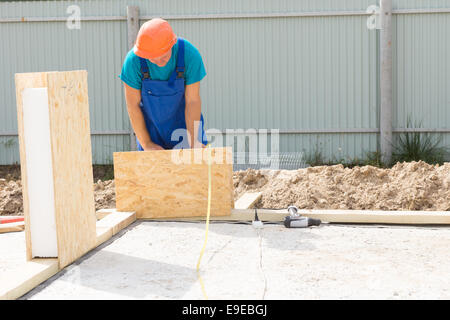Occupé Solo Male Construction Worker avec casque Orange Immobilier Construction maison wall. Banque D'Images