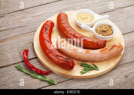 Saucisses grillées avec divers condiments on cutting board Banque D'Images