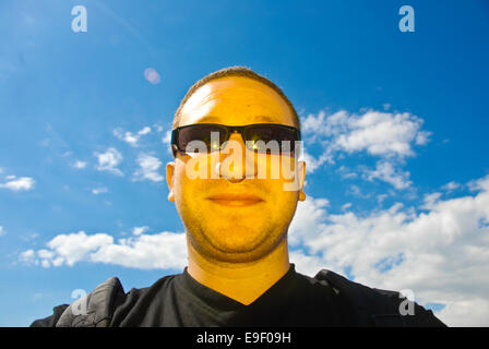 Un homme éclairé avec une lumière jaune se dresse contre un ciel bleu à la recherche comme le générique des Simpsons Banque D'Images