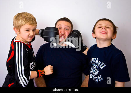 Deux enfants punch un homme au visage wearing boxing gloves Banque D'Images