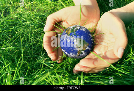 Les mains à terre globe on Green grass Banque D'Images