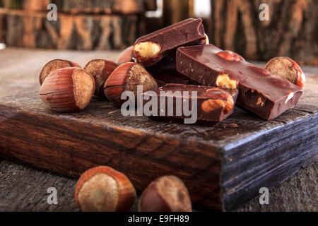 Pile de délicieuses barres de chocolat avec des fruits entiers sur bois, chaleureuse composition de morceaux de chocolat aux noisettes Banque D'Images