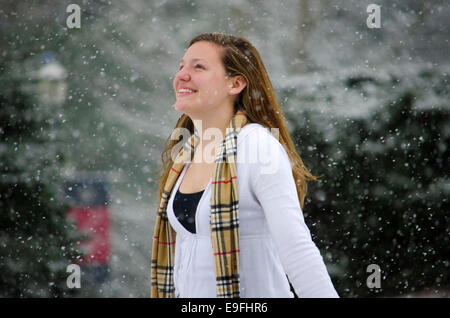 Let it Snow : Une jeune femme levait les bras en signe de victoire d'une belle averse de neige. Banque D'Images